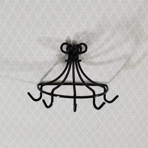 May include: A black metal wall-mounted rack featuring a semi-circular frame with five curved hooks extending downward. The top section consists of a central vertical support with decorative looped wire accents, designed for hanging various items.