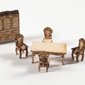 May include: Miniature wooden dollhouse furniture set. Includes a small cabinet, a rectangular table, and four ornate chairs. The furniture is made of light brown wood with gold-colored accents, perfect for a dollhouse or craft project.