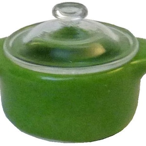 May include: A small, green ceramic casserole dish with a clear glass lid. The dish has two small handles and a clear glass knob on top of the lid. The casserole dish is a vibrant green color.