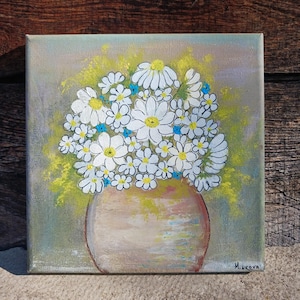 Op de afbeelding: Vierkant canvas schilderij van een boeket witte madeliefjes met gele centra en kleine blauwe bloemen in een bruinachtige vaas. De achtergrond is een mix van groene en gele tinten. Het schilderij is gesigneerd "Minkova".