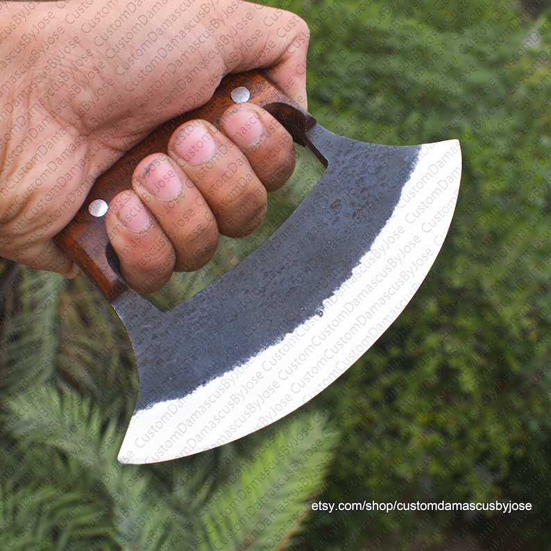 K&ouml;nnte beinhalten: Eine Hand h&auml;lt ein schwarzes und silbernes, gebogenes Messer mit einem Holzgriff. Das Messer hat eine abgerundete Klinge und eine kleine, spitze Spitze. Der Griff ist aus dunklem Holz mit einem hellen Holzakzent.