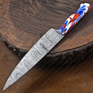 May include: A Damascus steel chef's knife with a blue, red, and white patterned handle. The blade is made of multiple layers of steel, creating a unique and beautiful pattern.
