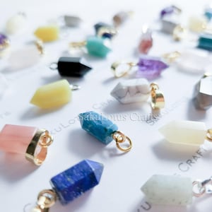 May include: Assortment of colorful crystal point pendants with gold-tone jump rings. The crystals are in various shapes and sizes, including amethyst, rose quartz, tiger's eye, and turquoise.