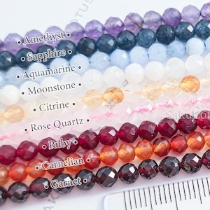 Peut inclure: Des rangées de perles de pierres précieuses à facettes de différentes couleurs, dont améthyste, saphir, aigue-marine, pierre de lune, citrine, quartz rose, rubis, cornaline et grenat. Une règle indique les mesures en centimètres.