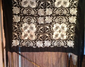 May include: A black shawl with intricate silver embroidery featuring floral and bird motifs. The shawl has a fringe border.
