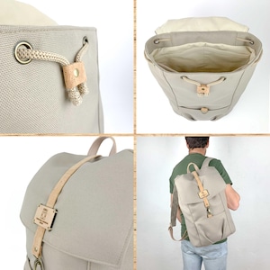 May include: A beige canvas backpack with leather straps and a cork accent. The backpack has a drawstring closure and a front pocket. The backpack is shown in different angles, including the inside of the bag.