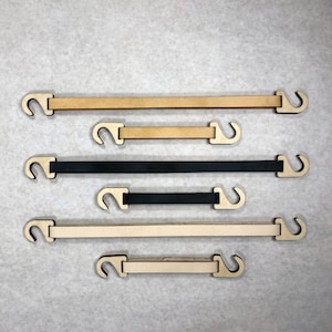 Op de afbeelding: Vijf houten banden met metalen haken. De banden zijn in verschillende lengtes en kleuren, waaronder zwart, bruin en beige.