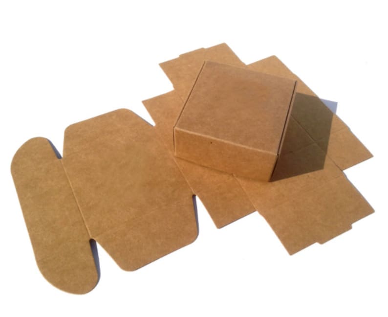 May include: A brown cardboard box with a square base and a flap that folds over the top. The box is unfolded and lying flat on a white surface.