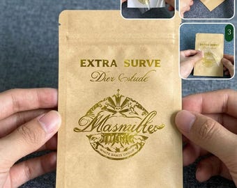 May include: A rectangular light brown kraft paper pouch featuring gold foil text that reads EXTRA SURVE, Dier Estude, and Masmiller White Shats Group. The pouch includes a resealable top strip and is shown with a gold foil sticker being applied.