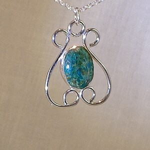 Eye-catching filigree pendant featuring an oval green chrysocolla stone in a bezel mount