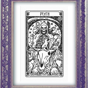 May include: Framed black and white cross-stitch art featuring the Death tarot card. The image shows a skeletal figure with a scythe, surrounded by other figures and the word "DEATH" at the top. The frame is ornate and purple.
