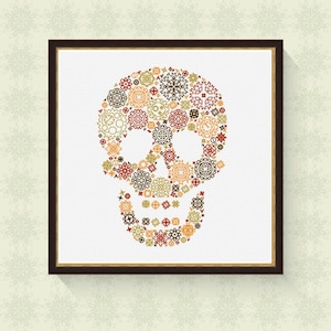 May include: A framed cross-stitch design of a skull made up of colourful geometric shapes. The skull is outlined in black and the background is white.