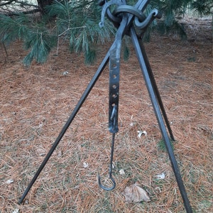 Peut inclure: Un tr&eacute;pied en m&eacute;tal noir avec un crochet et un anneau au sommet. Le tr&eacute;pied est pos&eacute; sur un lit d'aiguilles de pin.