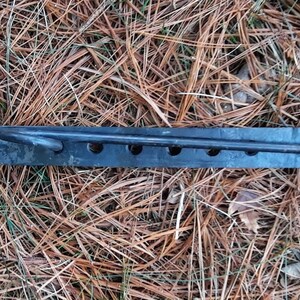 Peut inclure: Un crochet en m&eacute;tal noir avec une longue barre fine et deux crochets &agrave; chaque extr&eacute;mit&eacute;. La barre comporte cinq trous espac&eacute;s uniform&eacute;ment sur toute sa longueur.