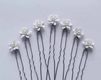 May include: Set of eight silver hair pins with white flower accents. Each flower has a pearl in the center.