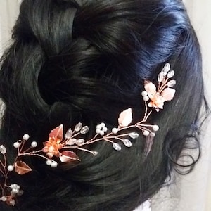 Könnte beinhalten: Ein Haarkamm aus Roségold mit zarten Blättern und weißen Perlen. Der Kamm ist so konzipiert, dass er für eine Hochzeit oder einen besonderen Anlass im Haar getragen werden kann.