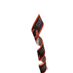 May include: A black and orange ribbon with the word "BEARS" printed on it. The ribbon is curled up and is hanging from the top of the image.