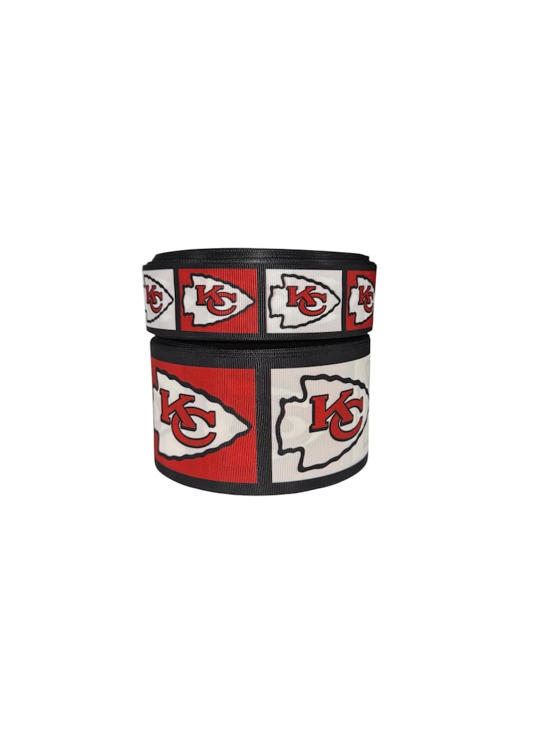 May include: Red, white, and black ribbon with a repeated pattern of the Kansas City Chiefs logo. The logo features an arrowhead with the letters "KC" inside.