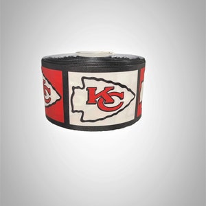 May include: A roll of black and white ribbon with a red and white Kansas City Chiefs logo printed on it.