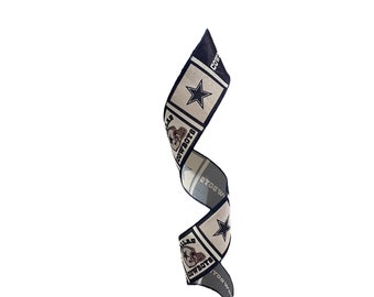 May include: A blue and white ribbon with the Dallas Cowboys logo and the words "Dallas Cowboys" repeated. The ribbon is curled and twisted.