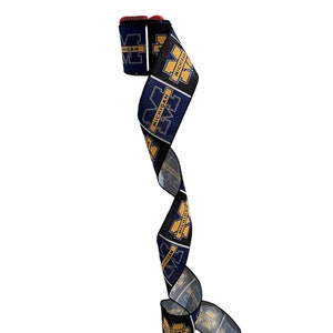 May include: A blue and gold ribbon with the University of Michigan logo repeated throughout. The ribbon is curled and ready to be used for wrapping gifts or decorating.