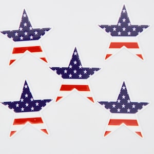 May include: Five blue and red star-shaped stickers with a white background. Each star features a design of the American flag.
