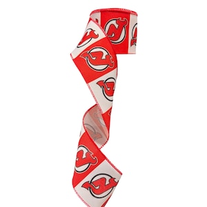 May include: A decorative ribbon featuring a repeating pattern of the New Jersey Devils hockey team logo. The design consists of alternating red and white square blocks, each containing the black, red, and white team emblem with stitched edges.
