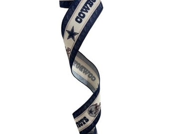 May include: A blue and white ribbon with the Dallas Cowboys logo and the words "Cowboys" and "Boys" repeated.