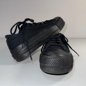 May include: A pair of black canvas low-top sneakers with a thick rubber sole.