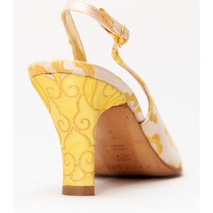 Puede incluir: Tacones amarillos y blancos con tira en el tobillo y un patr&oacute;n floral en el tac&oacute;n. El tac&oacute;n mide aproximadamente 7,5 cm de alto.