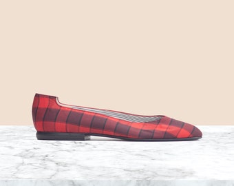 May include: Red and black plaid ballet flats with a pointed toe.