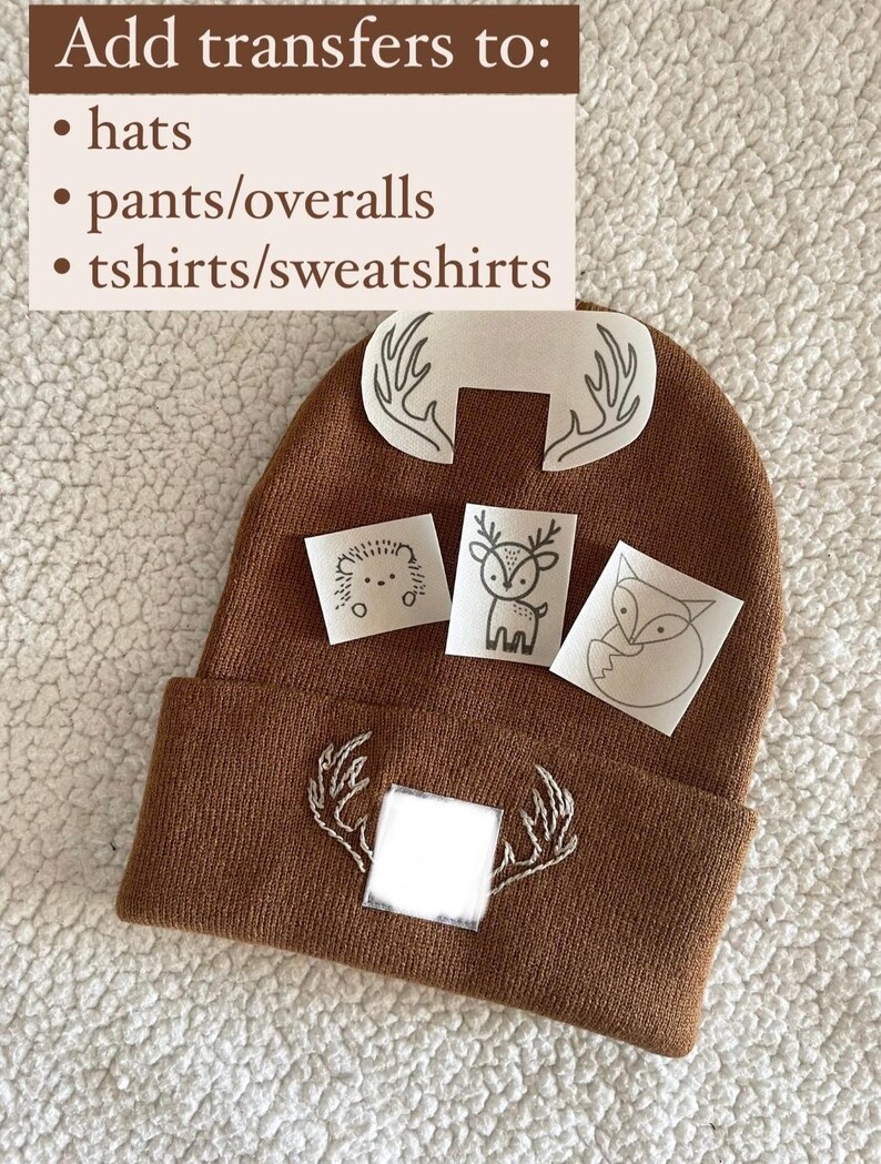May include: Brown knitted beanie with white embroidered antlers and a blank space for a transfer. The image also shows four iron-on transfers with animal designs: a deer, a fox, a hedgehog, and another set of antlers.