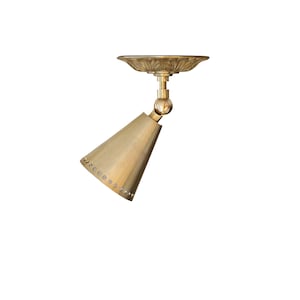 May include: A brass ceiling light fixture with a cone-shaped shade and a decorative base. The shade has a row of holes around the bottom edge.