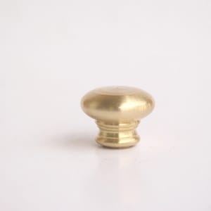 May include: A solid brass cabinet knob with a rounded top and a decorative base. The knob has a polished finish and is designed for use on drawers or cabinet doors. The hardware is a warm gold color.