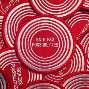 May include: Red and white circular embroidered patches with the text "Endless Possibilities" in white.