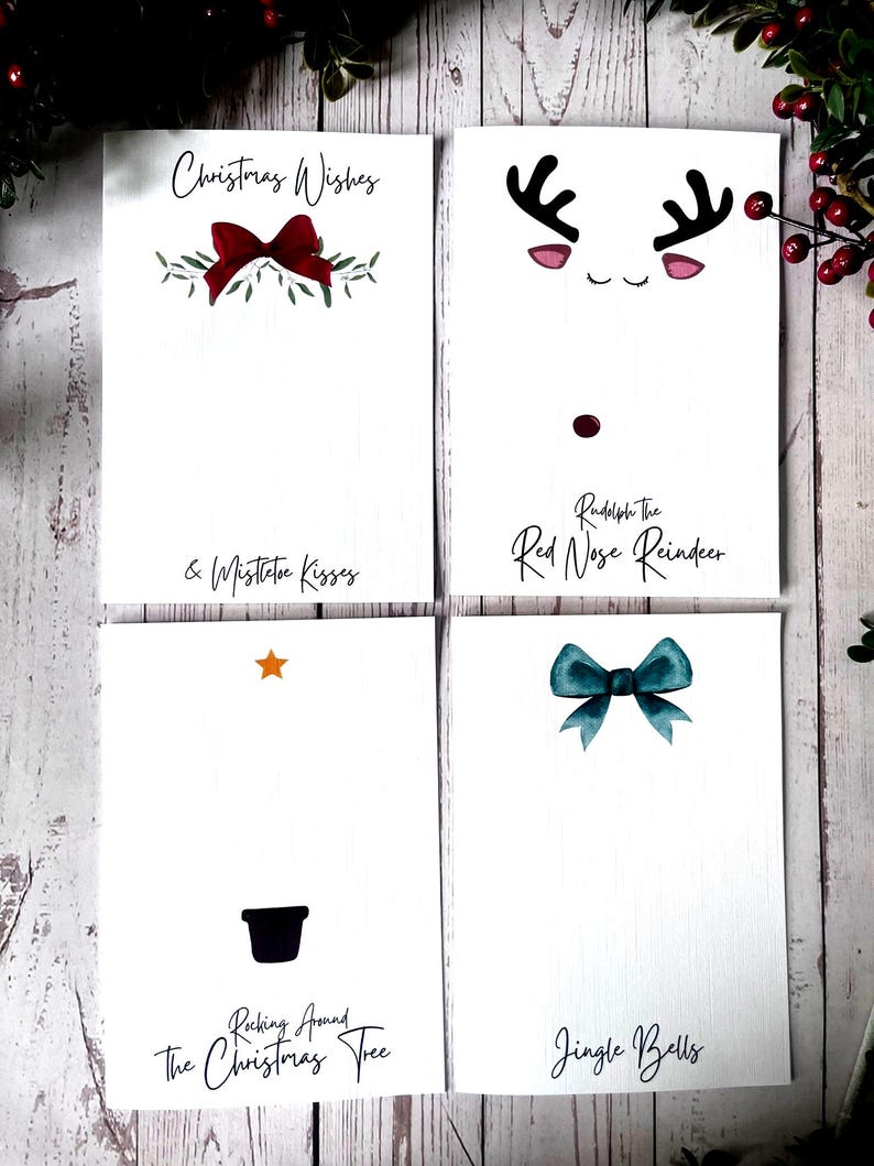 May include: Four printable Christmas card designs. The first card features a red bow with green leaves and the text "Christmas Wishes & Mistletoe Kisses". The second card features a cartoon reindeer with a red nose and the text "Rudolph The Red Nose Reindeer". The third card features a black silhouette of a Christmas tree with a star and the text "Rocking Around The Christmas Tree". The fourth card features a teal bow and the text "Jingle Bells".