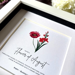 May include: A framed print with a red poppy and a pink gladiolus flower. The text reads "You're a Flower of August.  Symbolising a blend of strength, passion & emotional depth - you are strong & independent with a vibrant energy. Poppy - Gladiolus"