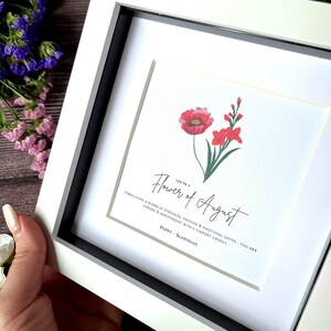 May include: A white framed print with a watercolor illustration of a poppy and gladiolus flower. The text reads "You're a Flower of August. Symbolising a blend of strength, passion & emotional depth. You are strong & independent with a vibrant energy. Poppy - Gladiolus"
