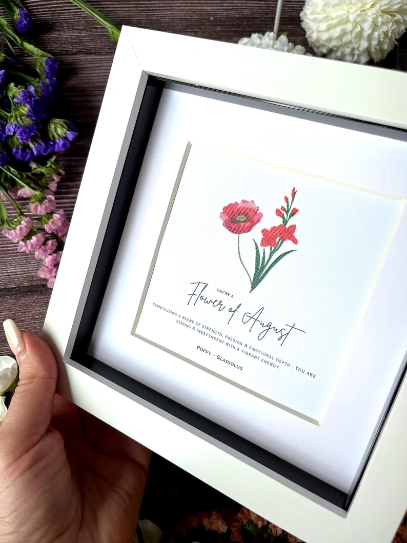 May include: A white framed print with a watercolor illustration of a poppy and gladiolus flower. The text reads "You're a Flower of August. Symbolising a blend of strength, passion & emotional depth. You are strong & independent with a vibrant energy. Poppy - Gladiolus"