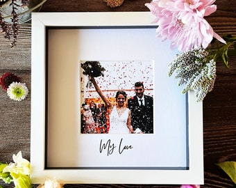 May include: A white picture frame with a photo of a bride and groom walking away from the camera, confetti falling around them. The photo is captioned "My Love".