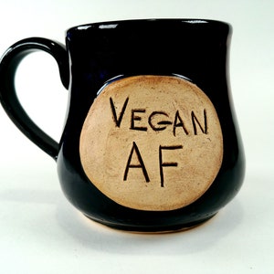 May include: A black ceramic mug with a tan circle on the side that says "VEGAN AF".