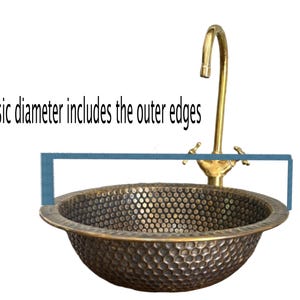 Custom made handmade brass sink: hammered copper bowl with rustic texture, tall luxe brass faucet on a wooden countertop.