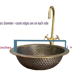 Custom made handmade brass sink: hammered copper bowl with rustic texture, tall luxe brass faucet on a wooden countertop.