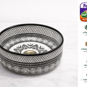 Round Moroccan ceramic vessel sink with hand-painted black-and-white geometric pattern and gold drain on a marble counter.