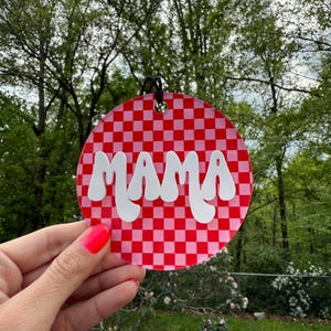 May include: A round, red and white checkered ornament with the word "MAMA" in white, cursive lettering.