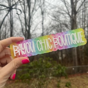 May include: A colorful tie-dye sticker with the text "Bayou Chic Boutique" in white lettering.