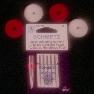 May include: A pack of 5 SCHMETZ Quick Threading Needles, with a purple background and white text. The needles are in a clear plastic case. The text on the package reads "SCHMETZ Quick Threading Needles Aiguilles à Enfilage Facile Agujas de Enhebrado Facil OHRSCHUITZ QUICK THREADING 05HD 80/12 5 PC/PZ".