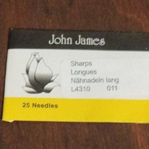 May include: A package of 25 John James Sharps Longues sewing needles, labeled "L4310 011" and "Nahnadeln lang". The package features a stylized flower design.