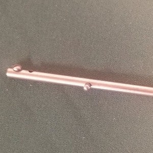 May include: A silver metal rod with two small round balls at each end.