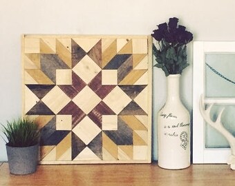 Puede incluir: Un tapiz de pared de madera con un patrón geométrico en tonos marrones, amarillos y rojos. El tapiz de pared se exhibe en una cómoda de madera con un jarrón de flores secas moradas, una ventana de cristal enmarcada en blanco y un cartel enmarcado con el texto "Be You" y una lista de afirmaciones positivas.